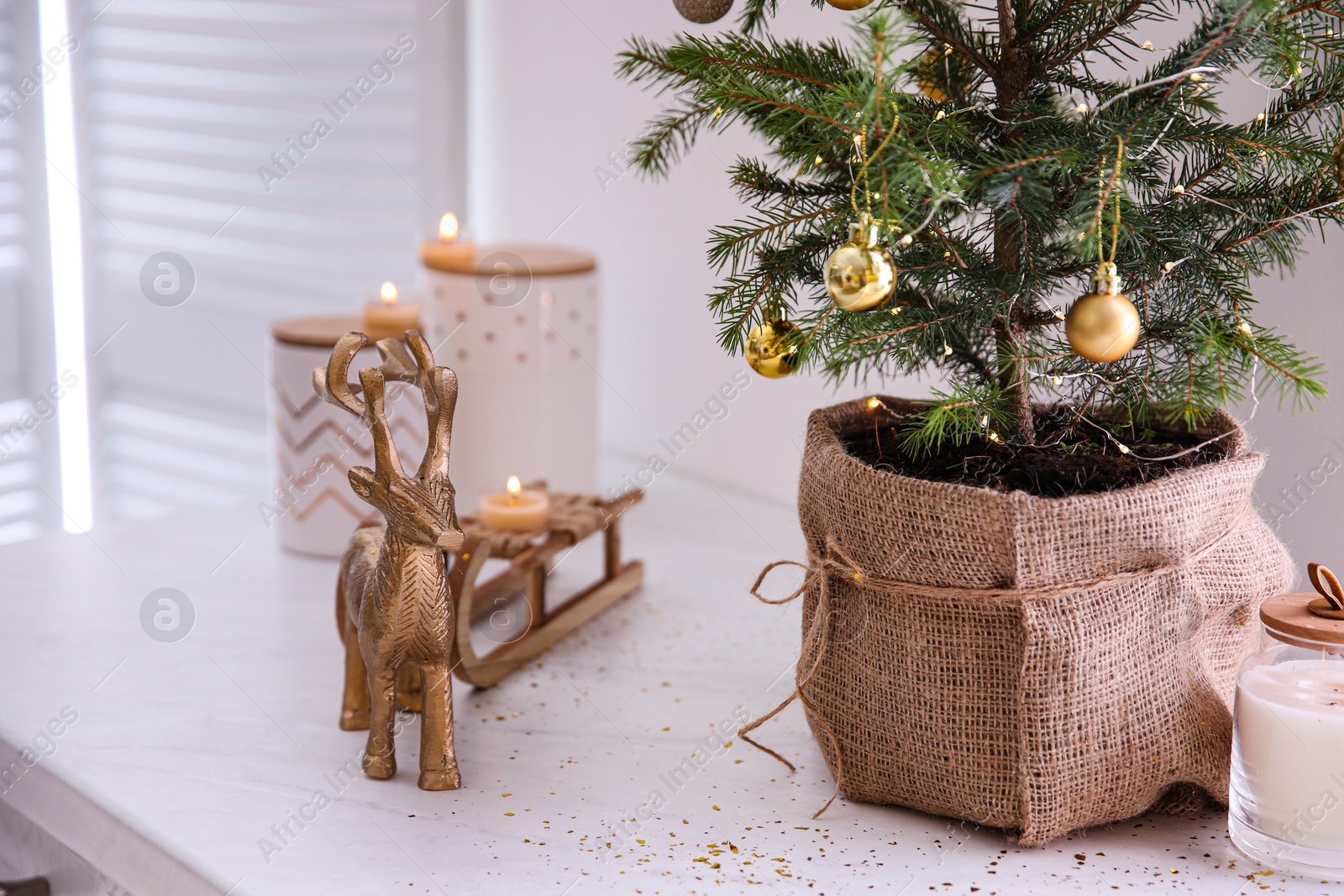 Photo of Small decorated Christmas tree and reindeer figure on countertop in kitchen, closeup