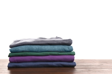 Pile of ironed clothes on table against white background. Space for text