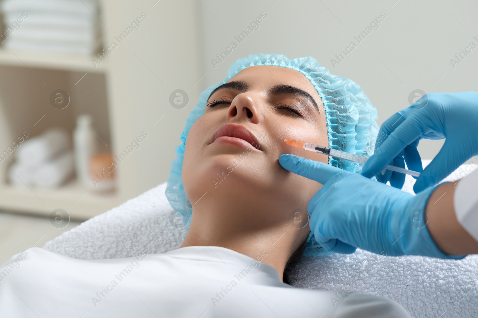 Photo of Doctor giving facial injection to young woman in clinic. Cosmetic surgery