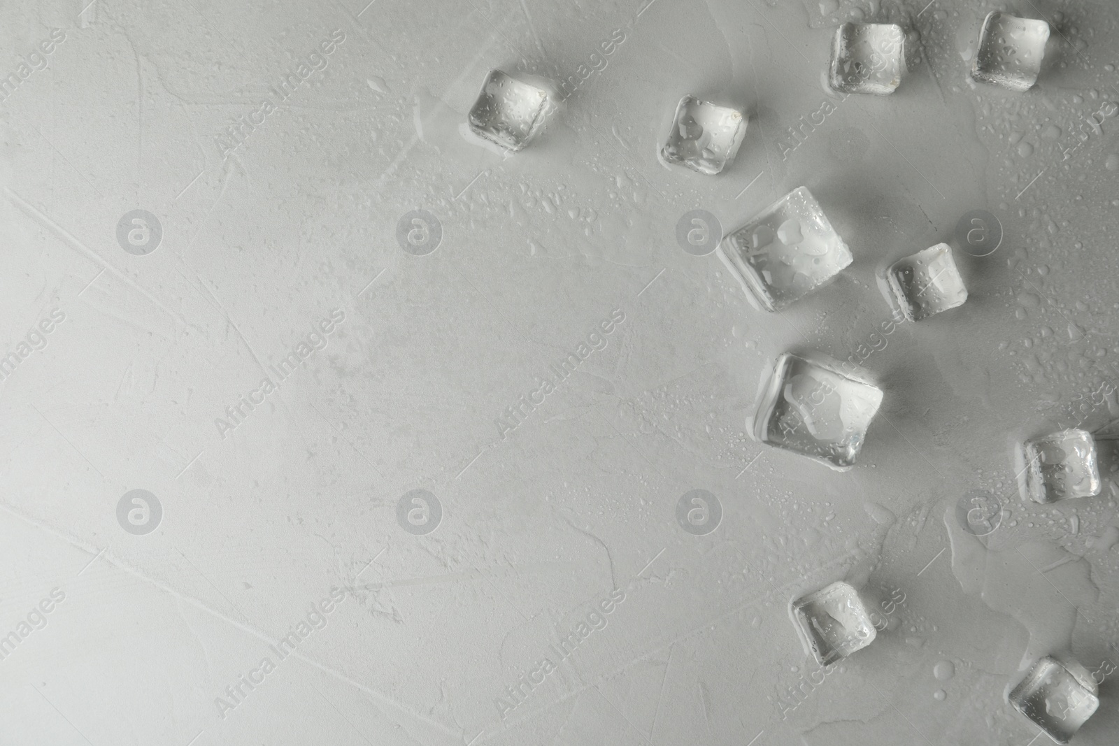 Photo of Crystal clear ice cubes with water drops on light grey table, flat lay. Space for text