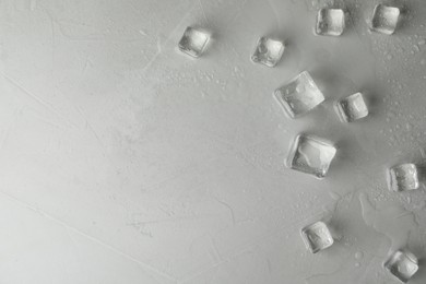 Photo of Crystal clear ice cubes with water drops on light grey table, flat lay. Space for text