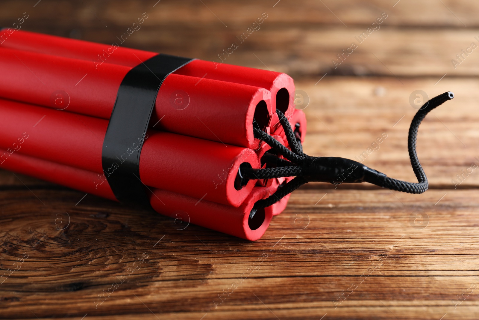 Photo of Red explosive dynamite bomb on wooden background, closeup