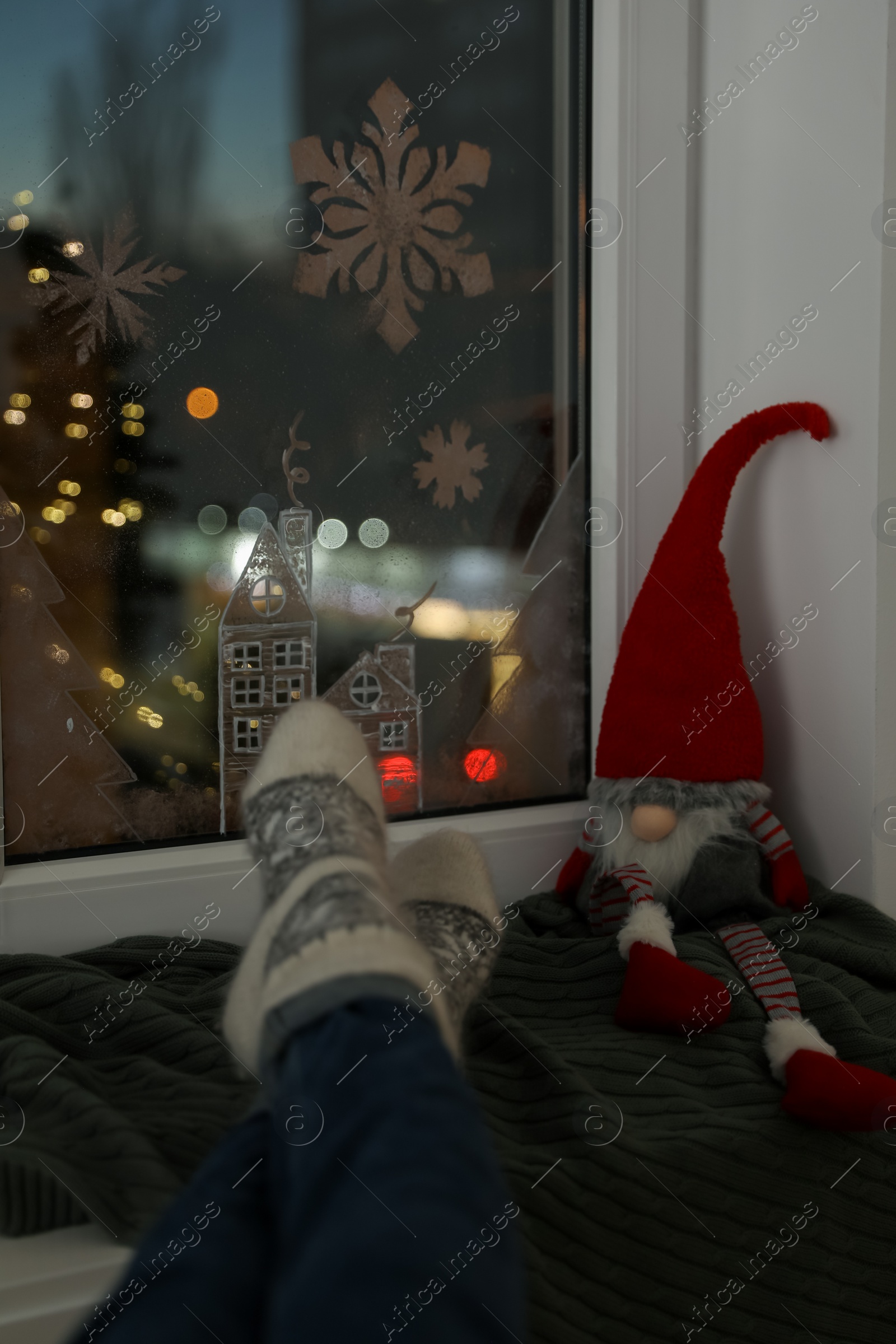 Photo of Woman resting near window with beautiful drawing at home, closeup. Christmas decor