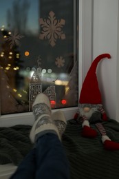 Woman resting near window with beautiful drawing at home, closeup. Christmas decor