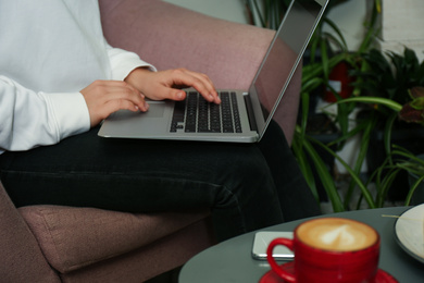 Photo of Blogger working with laptop in armchair indoors, closeup
