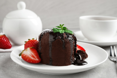 Delicious warm chocolate lava cake with mint and strawberries on table