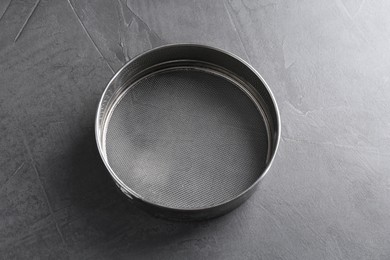 One metal sieve on grey table. Cooking utensil