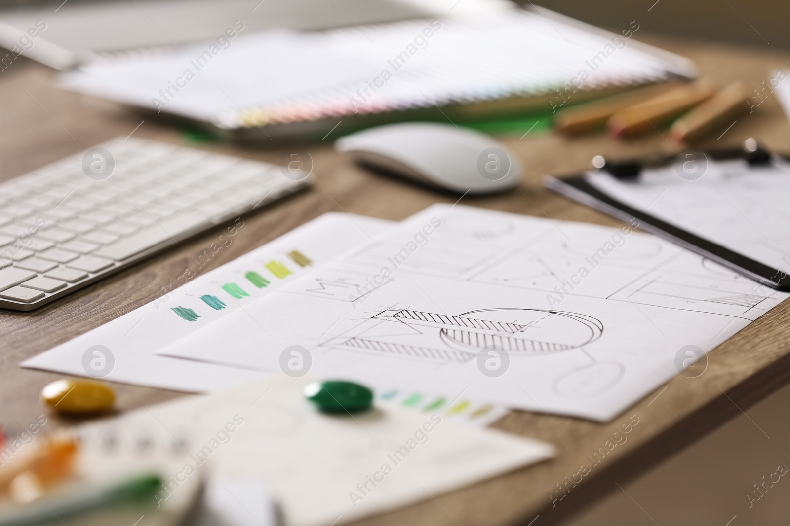 Photo of Sheets of paper with sketches on wooden table. Designer's workplace