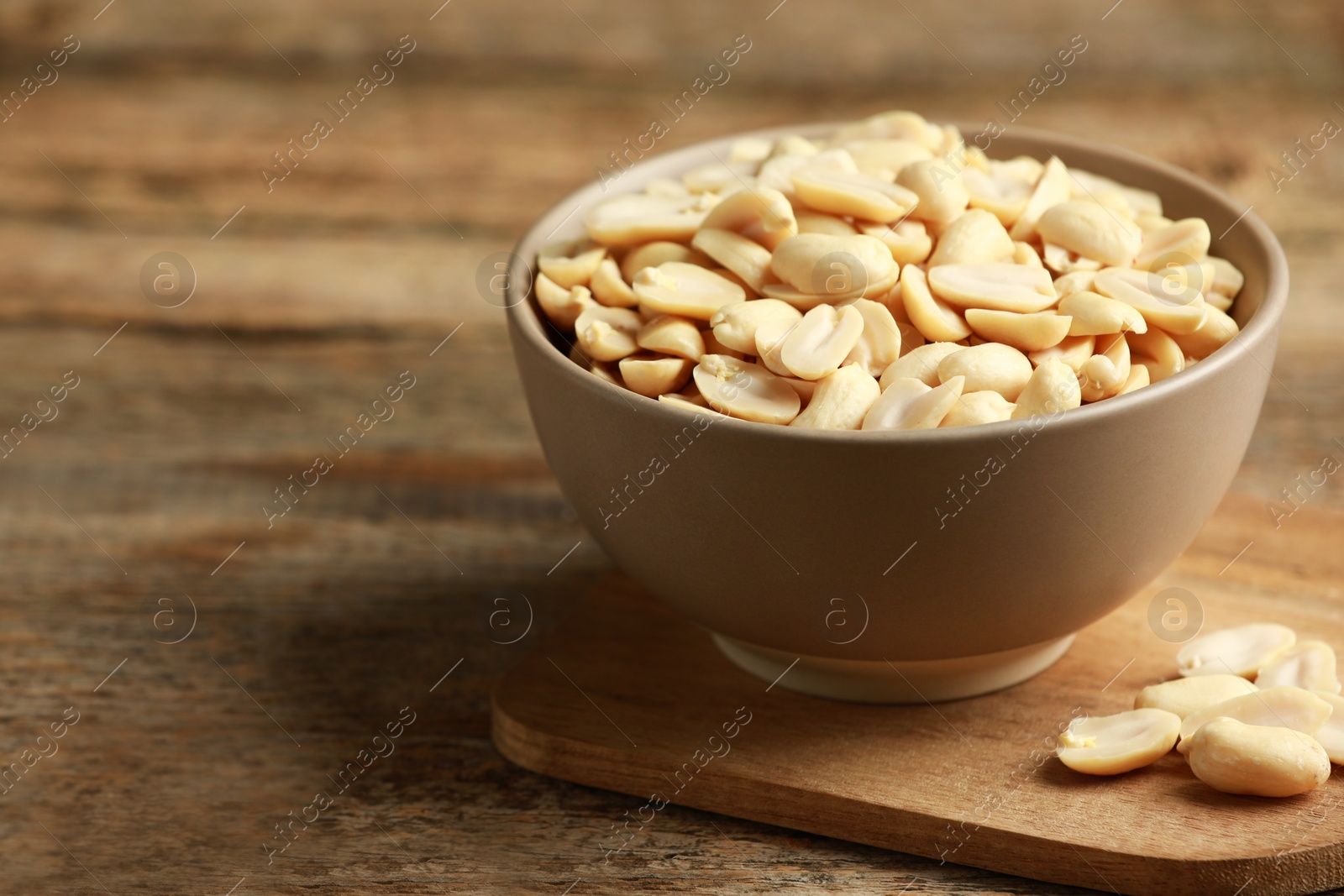 Photo of Fresh peanuts in bowl on wooden table, space for text