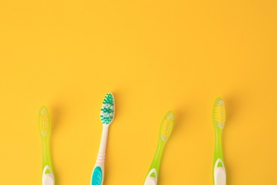 Photo of New toothbrushes on yellow background, flat lay. Space for text