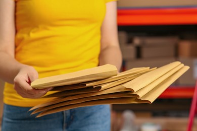 Photo of Post office worker with adhesive paper bags indoors, closeup