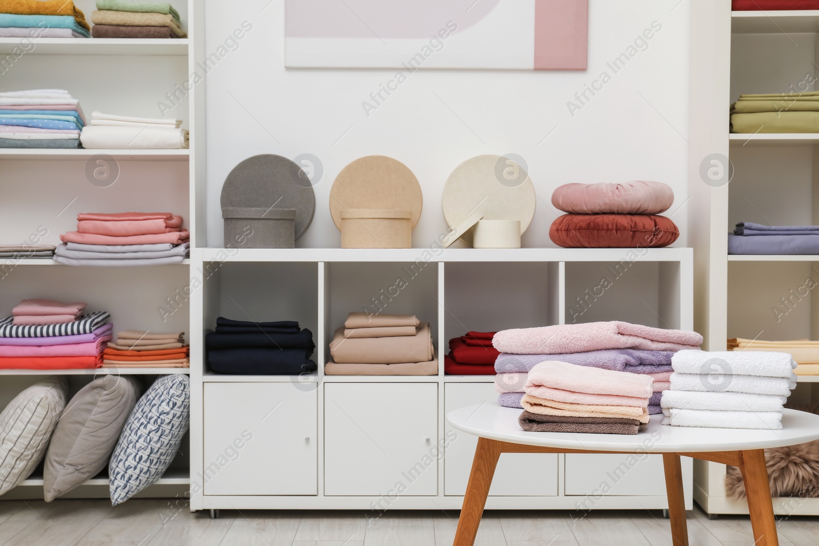 Photo of Stacked towels, decorative boxes, pillows and colorful bed linens in home textiles store