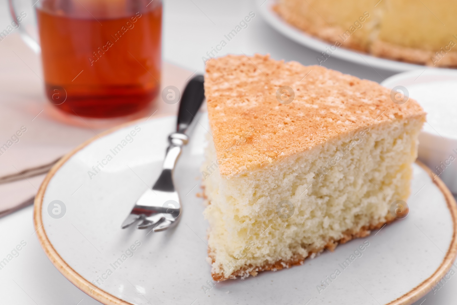 Photo of Piece of tasty sponge cake on white table, closeup