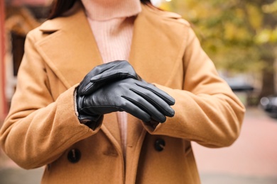 Photo of Young woman in black leather gloves, closeup. Stylish clothes