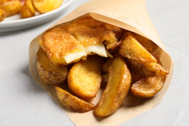 British traditional fish and potato chips in paper cone on table, closeup