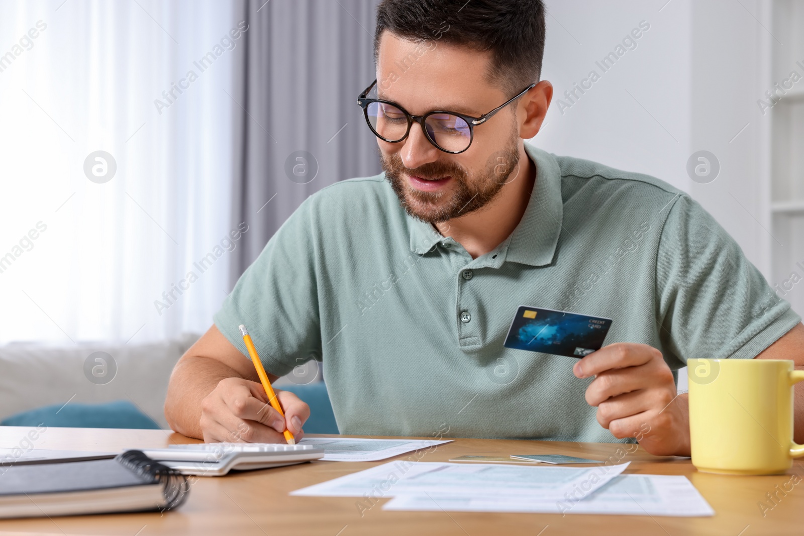 Photo of Man with credit card using laptop for paying taxes online at home, closeup