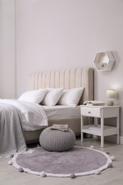Photo of Stylish bedroom interior with knitted pouf and furniture