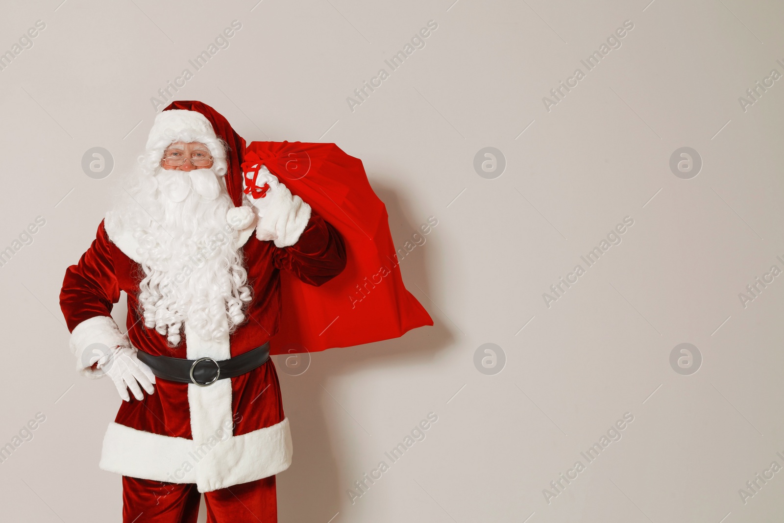 Photo of Authentic Santa Claus with bag full of gifts on grey background. Space for text