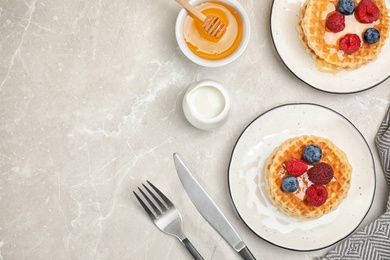Photo of Delicious breakfast with waffles, honey and berries on light table, flat lay. Space for text