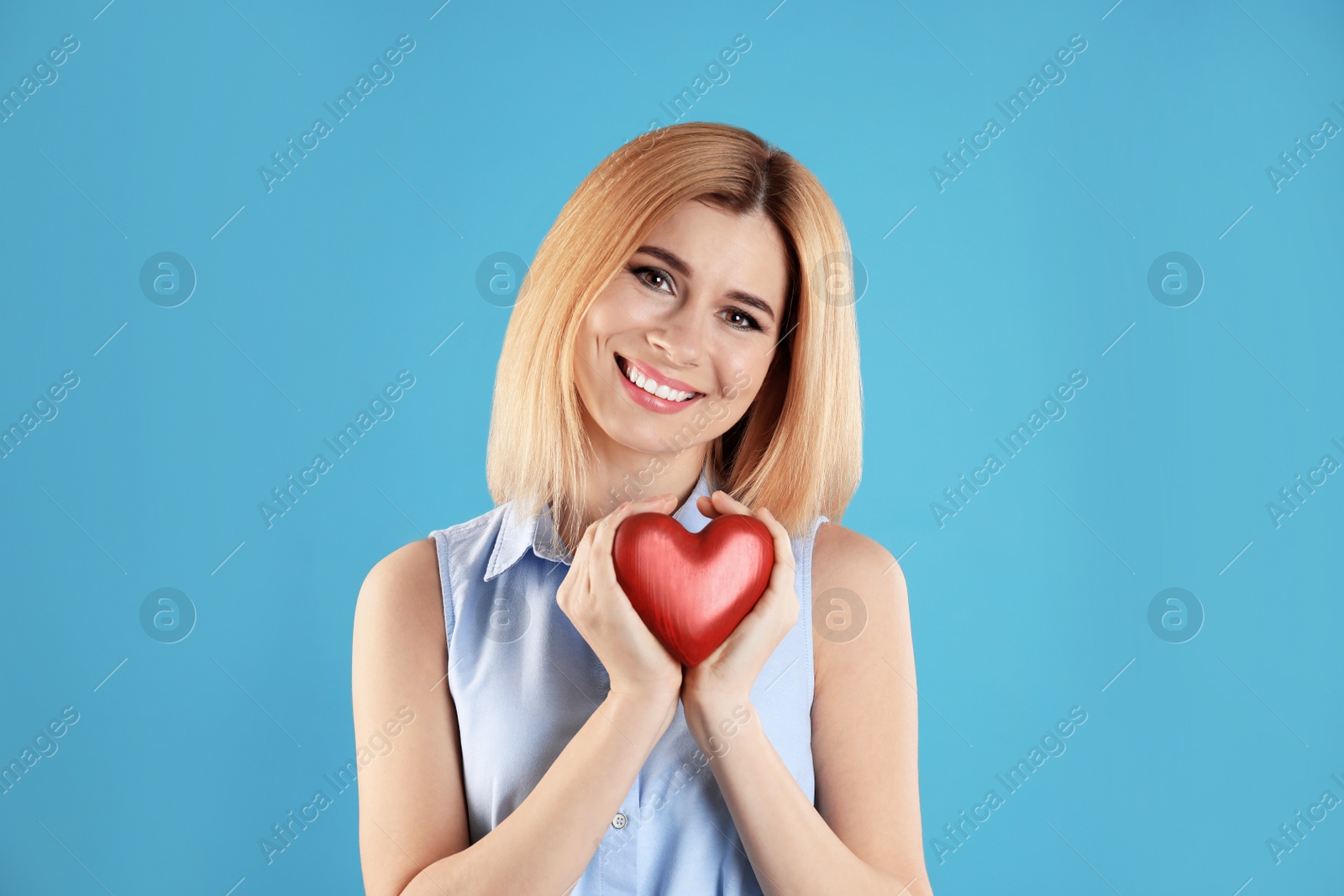 Photo of Portrait of beautiful woman holding decorative heart on color background