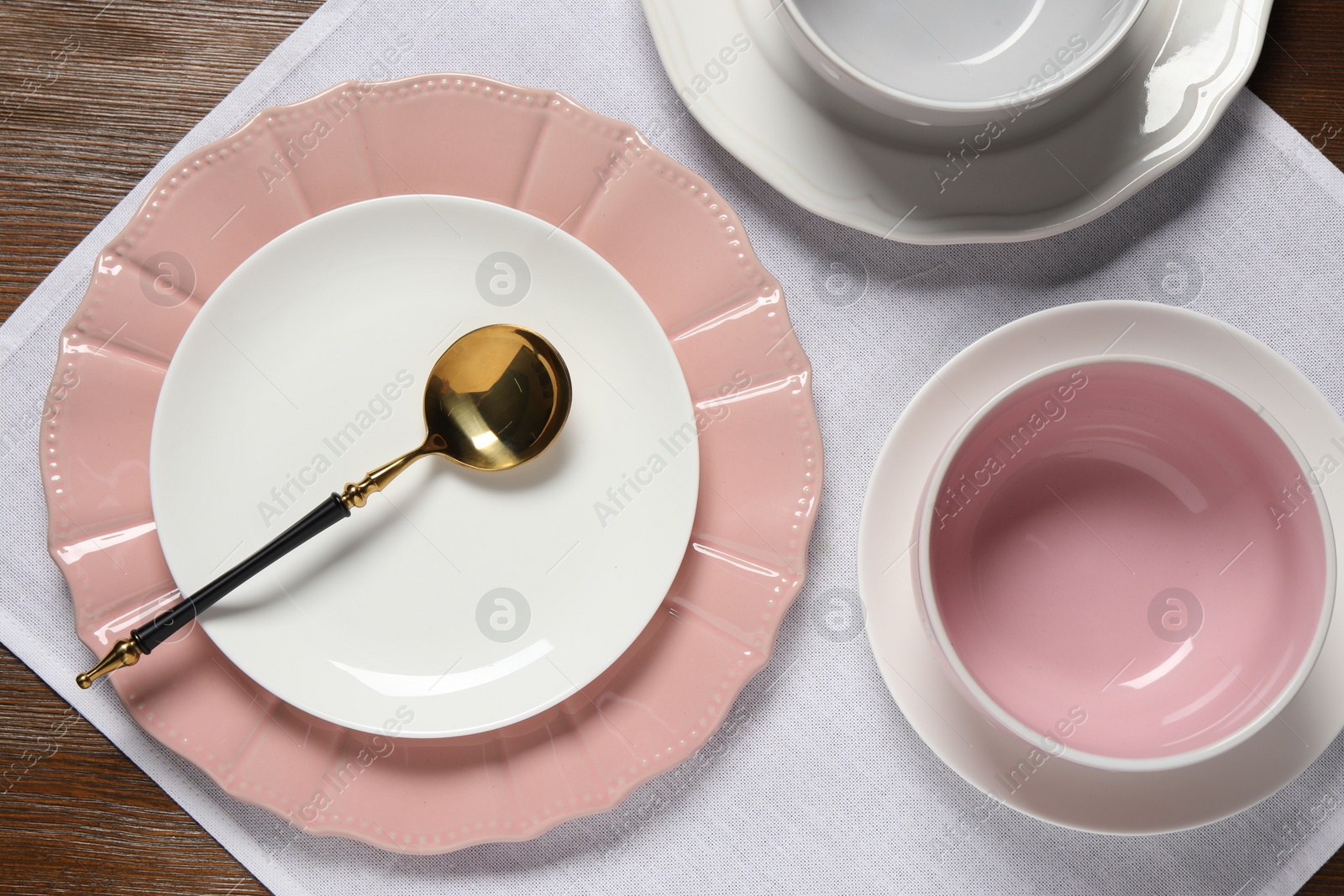 Photo of Beautiful ceramic dishware and spoon on wooden table, top view