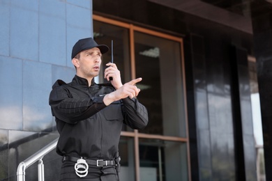 Photo of Male security guard using portable radio transmitter outdoors