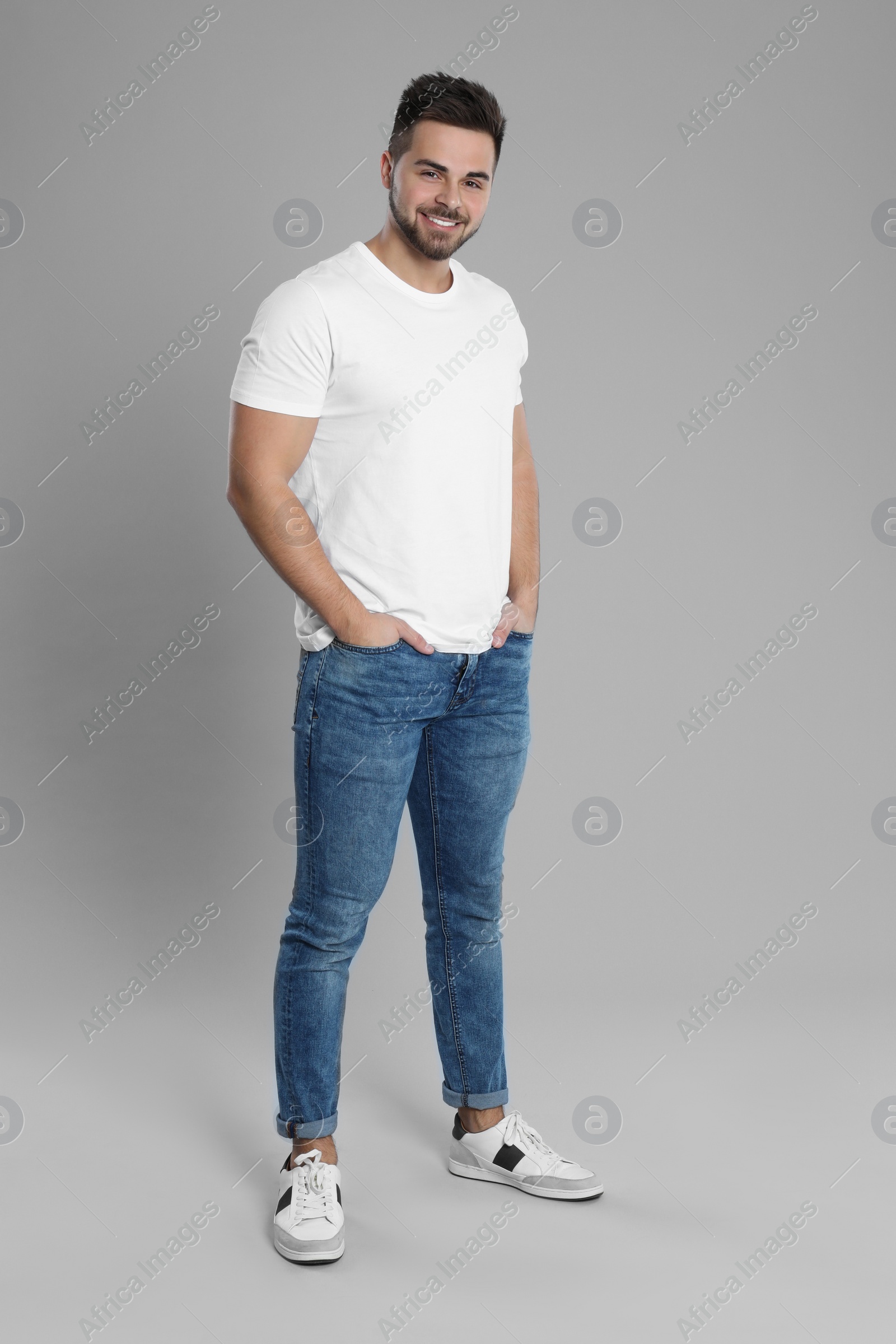 Photo of Young man in stylish jeans on grey background