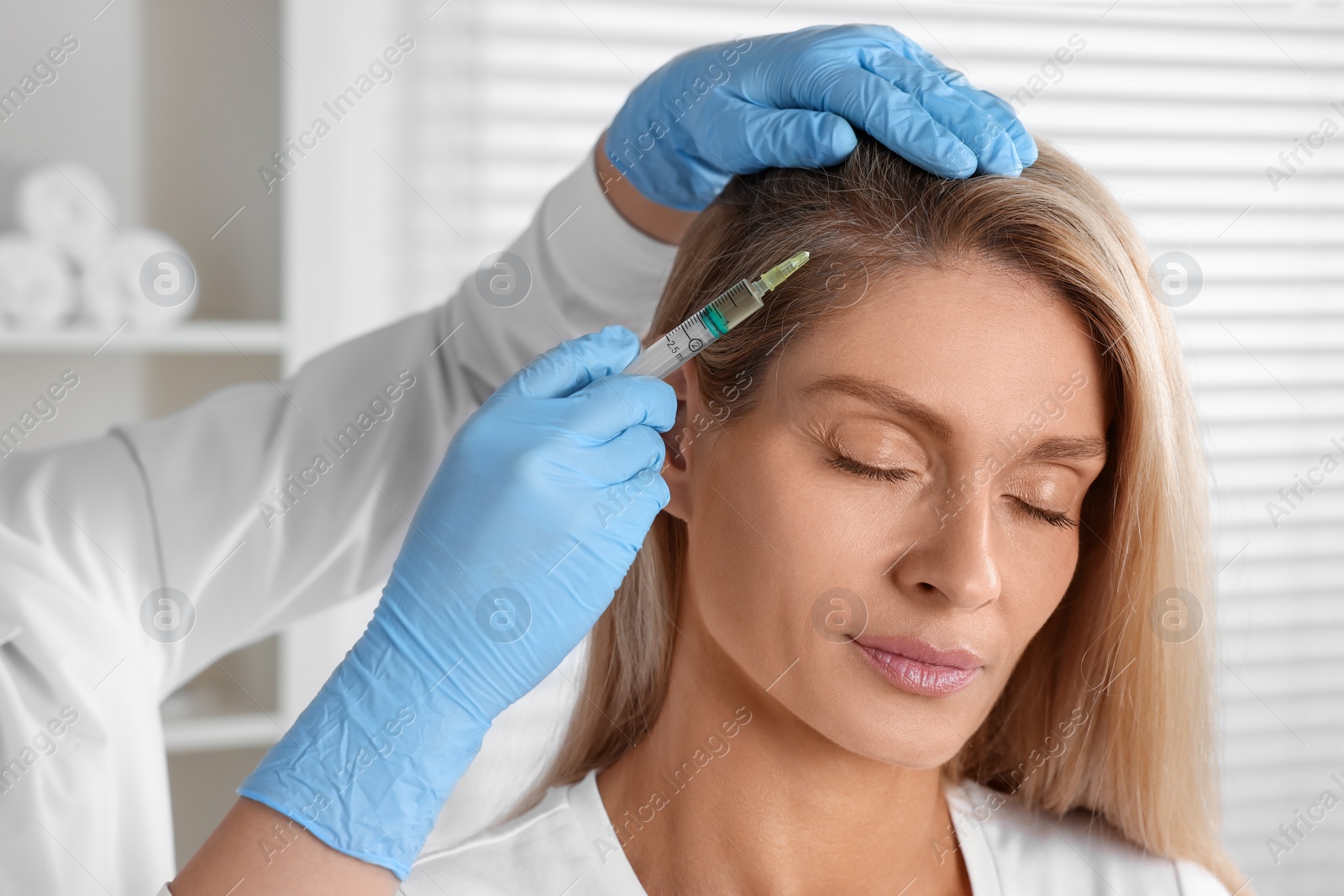 Photo of Trichologist giving injection to patient in clinic, closeup