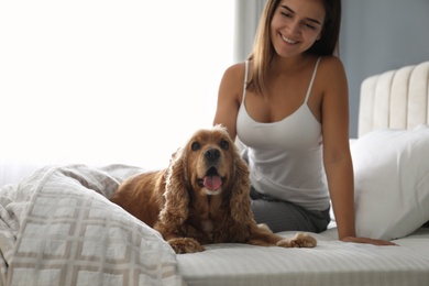 Photo of Young woman and her English Cocker Spaniel on bed indoors. Pet friendly hotel