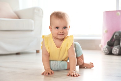 Photo of Cute baby girl sitting on floor in room