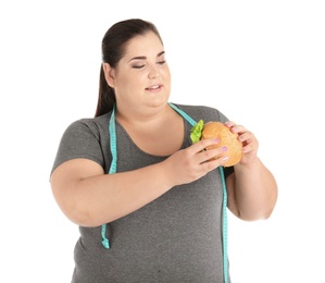 Photo of Overweight woman with hamburger and measuring tape on white background