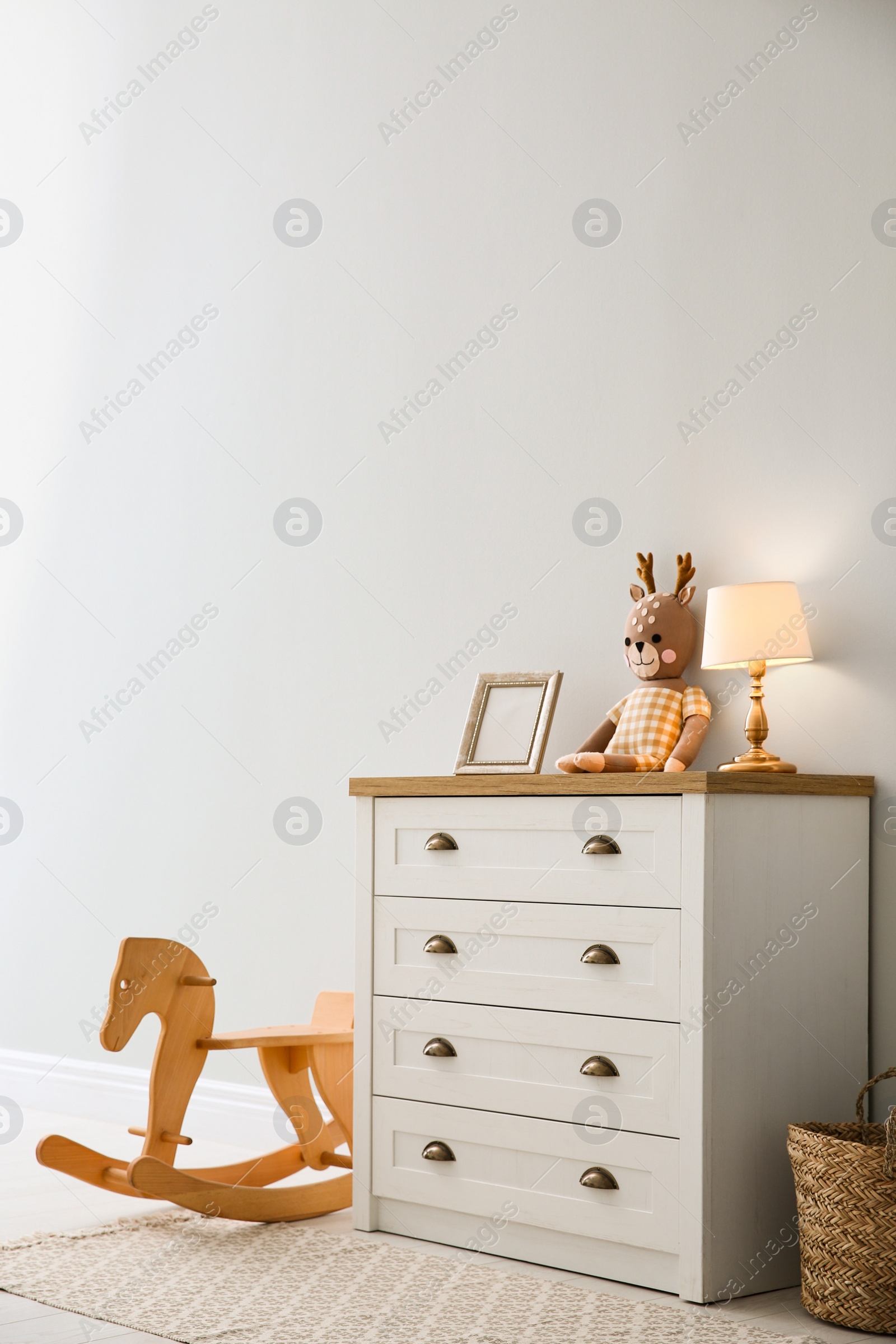 Photo of Modern white chest of drawers near light wall in child room. Interior design