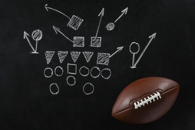 Photo of Leather American football on chalkboard with scheme of game, top view