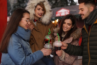 Friends with cups of mulled wine at winter fair