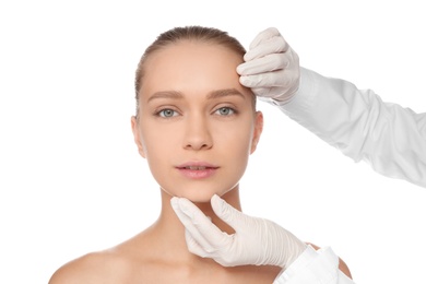 Photo of Doctor examining young woman face before cosmetic surgery on white background