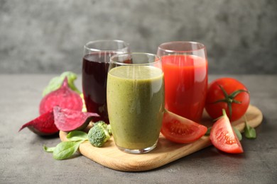 Photo of Delicious vegetable juices and fresh ingredients on grey table