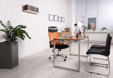 Photo of Stylish director's workplace with comfortable desk, computer and chairs for visitors in office. Interior design