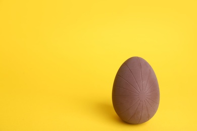 Sweet chocolate egg on yellow background. Space for text