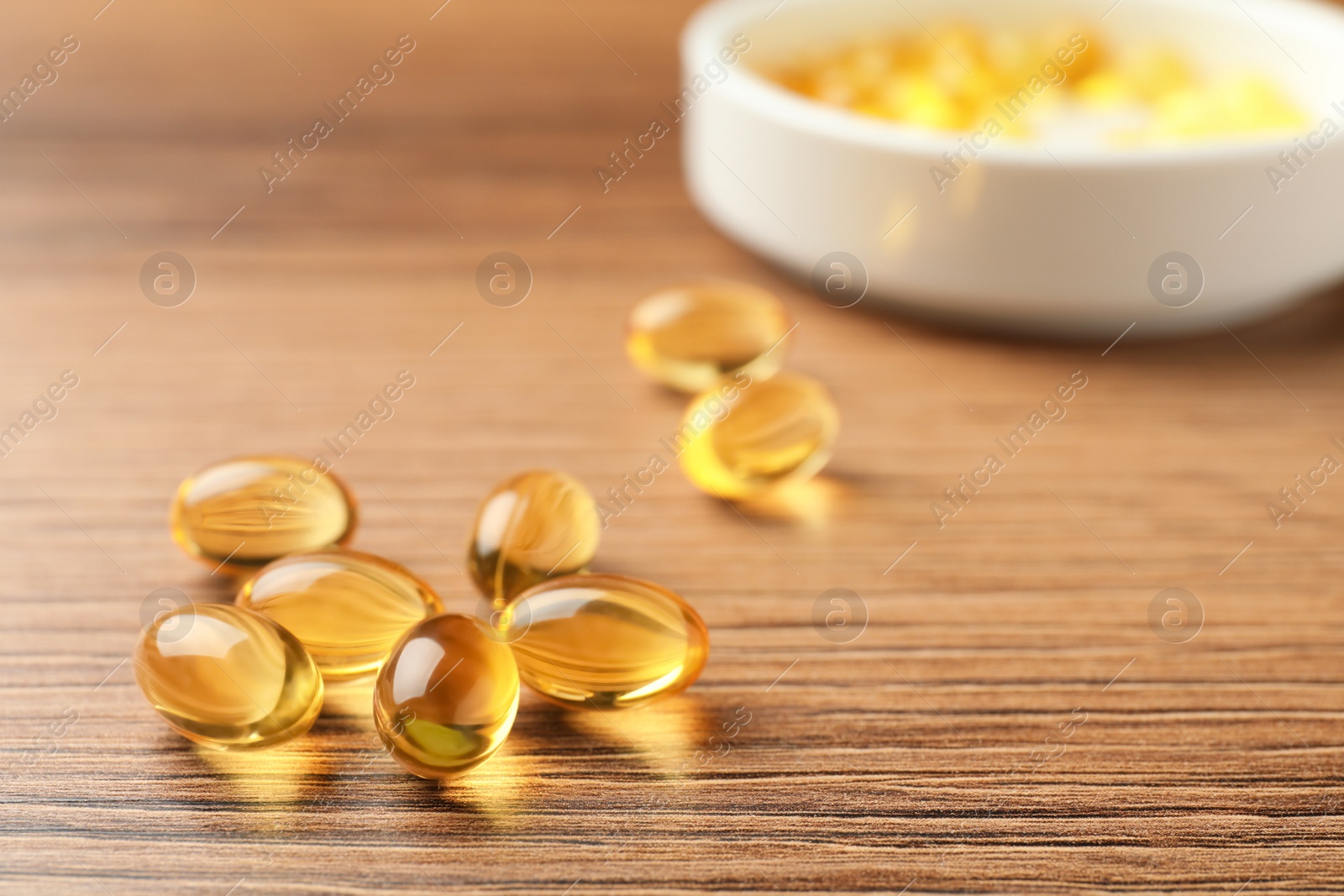 Photo of Dietary supplement capsules on wooden table, closeup. Space for text