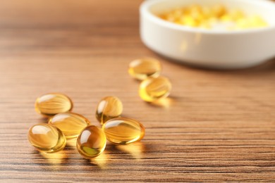 Dietary supplement capsules on wooden table, closeup. Space for text