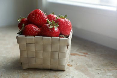 Photo of Fresh juicy strawberries in wicker basket on windowsill, closeup