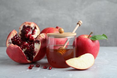 Photo of Honey, pomegranate and apples on grey marble table. Rosh Hashana holiday