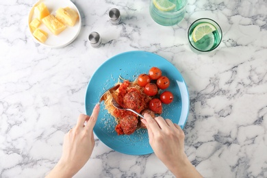 Woman having pasta with meatballs and tomato sauce at table, closeup