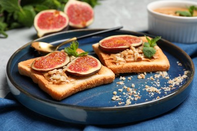 Photo of Tasty toasts served with fig, peanut butter and walnuts on light grey table, closeup