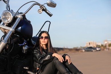 Beautiful woman sitting near motorcycle on sunny day