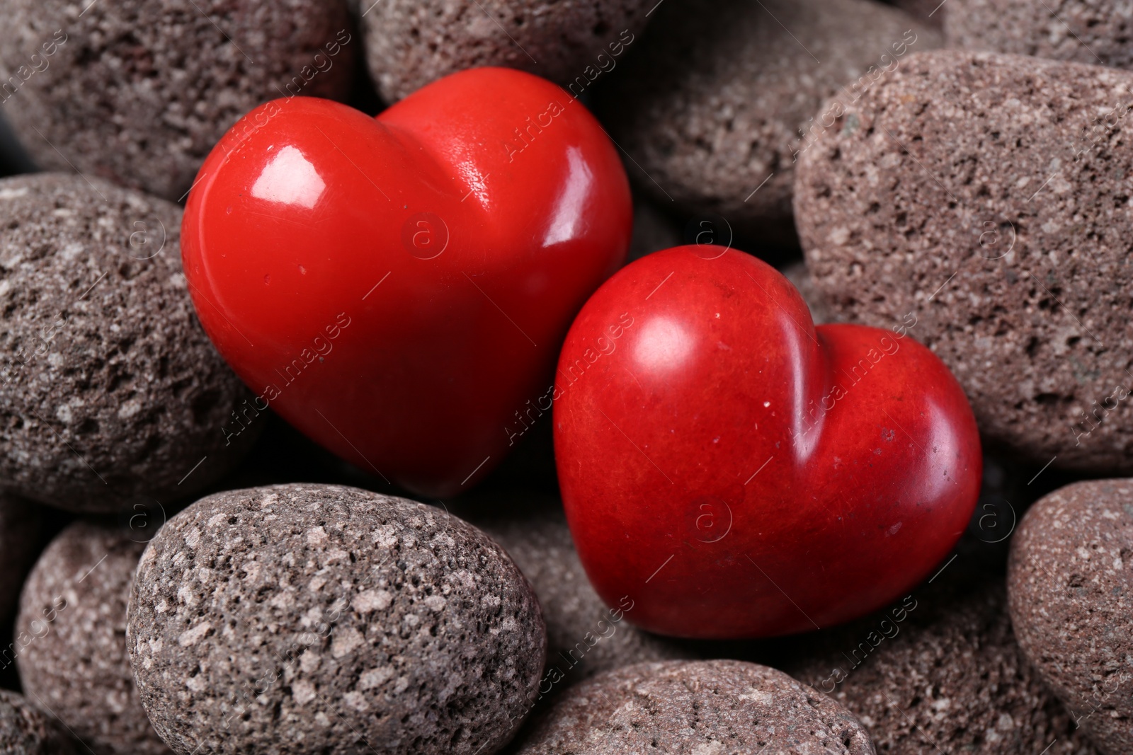 Photo of Red decorative hearts on stones, closeup view