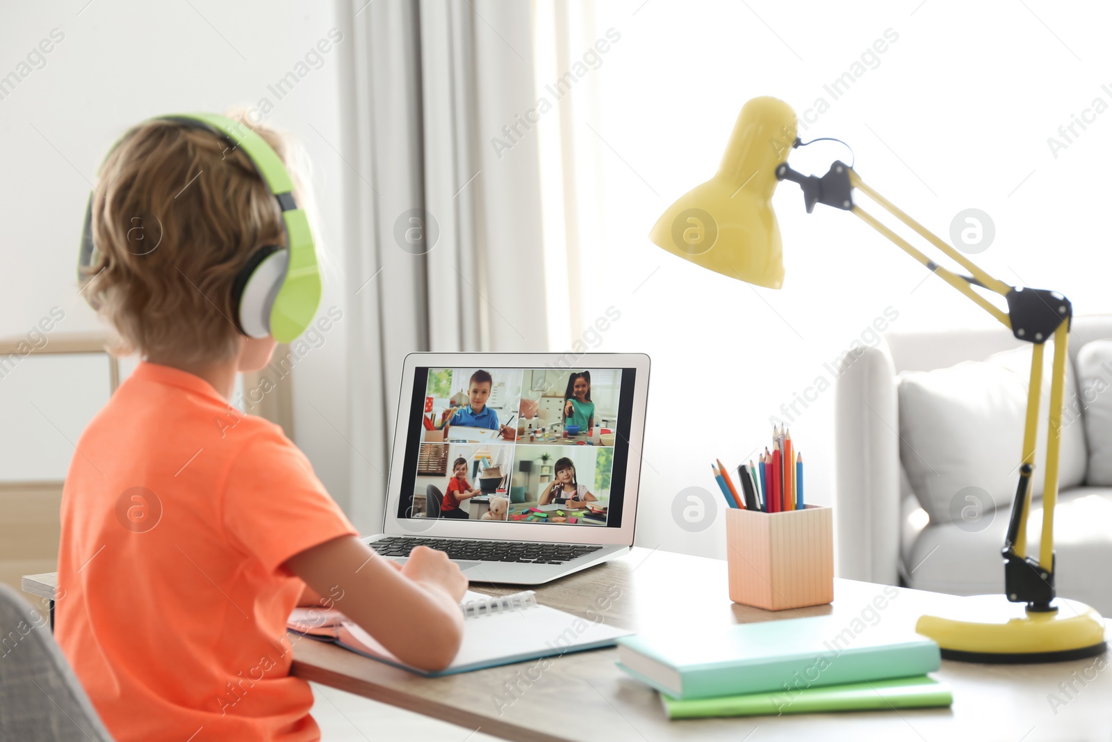 Photo of Little boy studying with classmates via video conference at home. Distance learning during COVID-19 pandemic