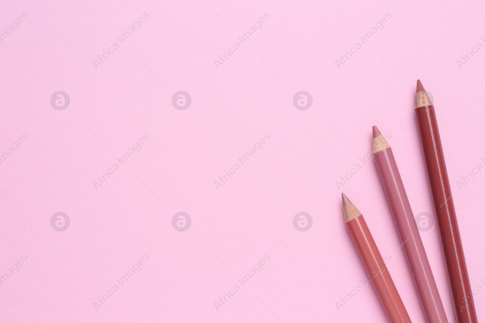 Photo of Lip pencils on pink background, flat lay with space for text. Cosmetic product