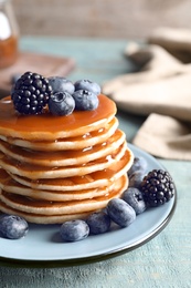 Photo of Tasty pancakes with berries and syrup on plate