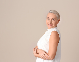 Portrait of beautiful mature woman on beige background. Space for text